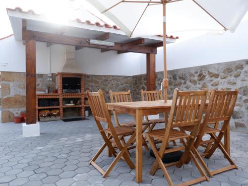 a wooden table and chairs with an umbrella at Casa da Rabita in Capinha