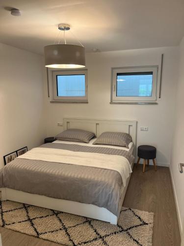 a bedroom with a large bed and two windows at Modernes Apartment mit großer Terrasse & Parkplatz in Schwäbisch Hall
