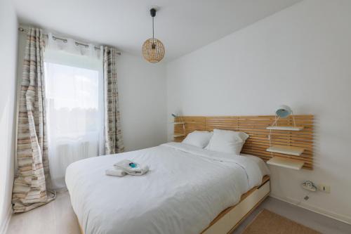 a white bedroom with a bed with a towel on it at Family Elegance - Comfort & Garden in Cormeilles-en-Parisis