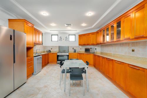 a kitchen with wooden cabinets and a table with chairs at Palm Villa F, Palm Jumeirah - Mint Stay in Dubai