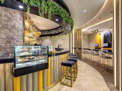 a restaurant with a counter with stools and a bar at ibis Styles Johor Iskandar Puteri in Johor Bahru