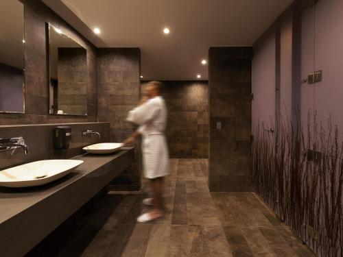 a woman standing in a bathroom with two sinks at Novotel Vina del Mar in Viña del Mar