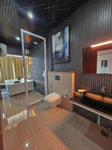 a bathroom with a toilet and a sink and a tub at Panoramic Jacuzzi Suite with huge Balcony & Swing in Mussoorie