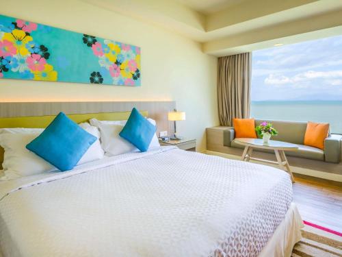 a bedroom with a bed and a couch and a window at Mercure Penang Beach in George Town