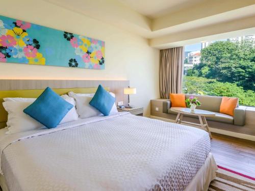 a bedroom with a bed and a couch and a window at Mercure Penang Beach in George Town