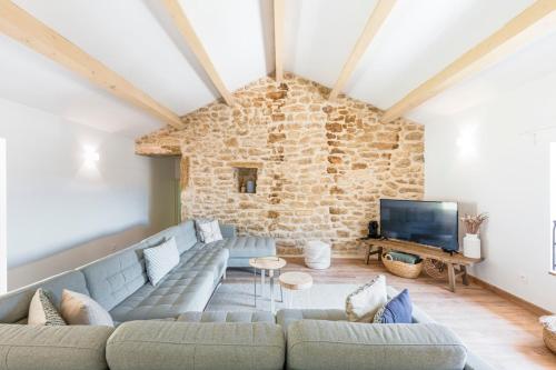 a living room with a couch and a stone wall at La Bastide du Père Mathieu Jacuzzi couvert et Piscine in Suze-la-Rousse
