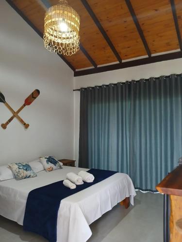a bedroom with a bed with a chandelier and a blue curtain at Pousada Atlantik-Haus in Costa Dourada