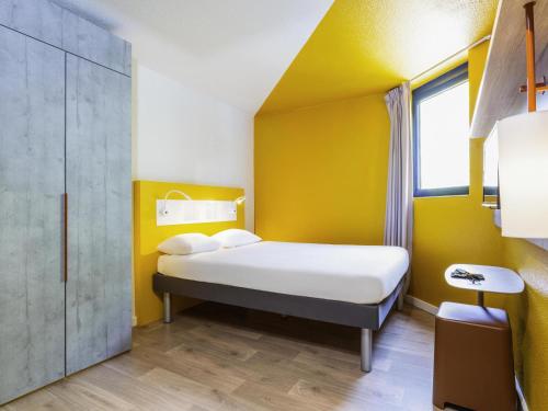 a room with a bed and a yellow wall at ibis budget Marne La Vallée Noisy Le Grand in Noisy-le-Grand