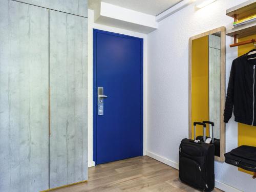 a blue door in a room with a suitcase at ibis budget Marne La Vallée Noisy Le Grand in Noisy-le-Grand