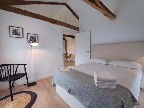 a white bedroom with a bed and a chair at M1 Preciosa casa reformada con gran patio exterior in Ourense