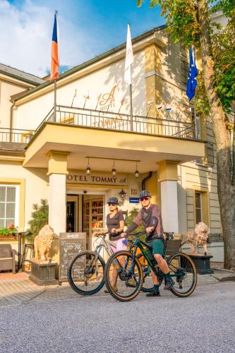 2 personnes en vélo devant un bâtiment dans l'établissement Hotel Tommy Wellness & Spa, à Náchod