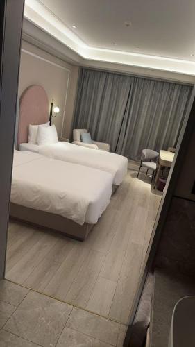 a hotel room with two beds and a mirror at Mercure Guangzhou Financial City in Guangzhou