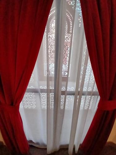 Qurum Heights Hotel في مسقط: نافذة مع ستائر حمراء في الغرفة