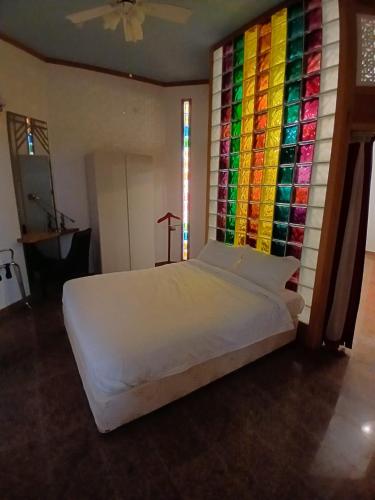 1 dormitorio con cama blanca y pared colorida en Qurum Heights Hotel, en Mascate