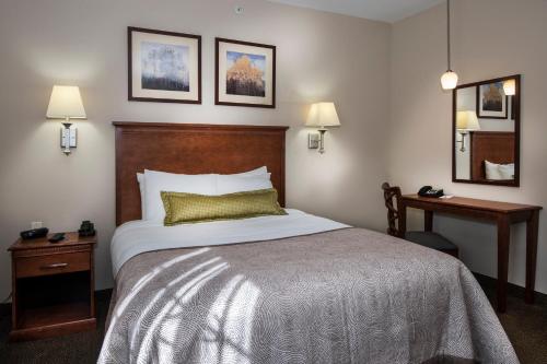 a hotel room with a bed and a table and a mirror at Candlewood Suites Conway by IHG in Conway