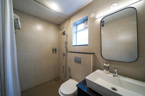 a bathroom with a sink and a toilet and a mirror at Olive Hotel Indiranagar 100Ft Road by Embassy Group in Bengaluru