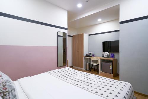 a bedroom with a bed and a desk with a television at Olive Hotel Indiranagar 100Ft Road by Embassy Group in Bengaluru