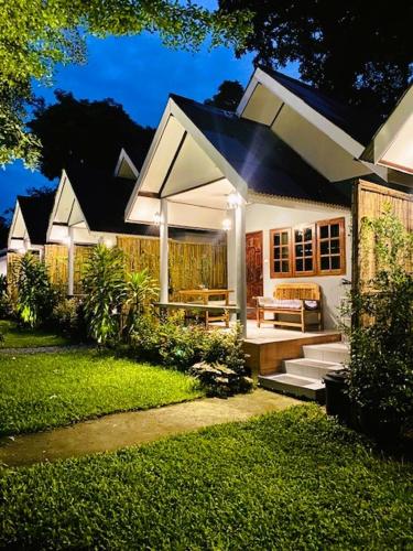 a white house with a porch with a bench in a yard at THARA PHLU BUNGALOWS Koh Chang in Ko Chang