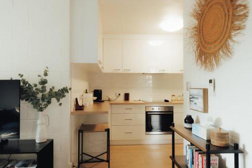 Una cocina con gabinetes blancos y una mesa en ella. en Parkside Apartment Near CBD & City Park with Parking, en Launceston