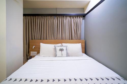 a bedroom with a bed with white sheets and a window at Olive Hotel Indiranagar 100Ft Road by Embassy Group in Bengaluru