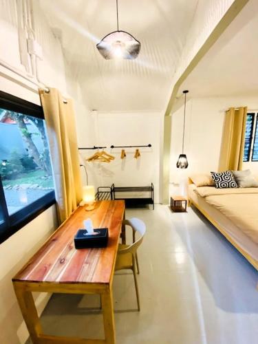 a living room with a wooden table and a bed at THARA PHLU BUNGALOWS Koh Chang in Ko Chang