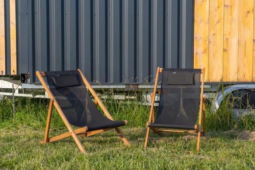 two chairs sitting in the grass next to a building at Tiny-House - 5 min de Montélimar - Salle de bain italienne & grand confort in Châteauneuf-du-Rhône