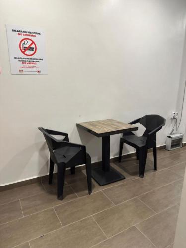 a table and two chairs and a sign on a wall at LM Motel in Kulim
