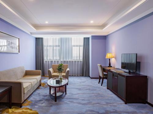 a living room with a couch and a tv at Novotel Guiyang Panjiang in Guiyang