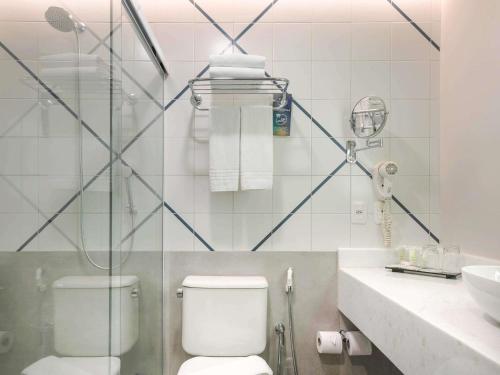 a bathroom with a toilet and a sink at Novotel Salvador Rio Vermelho in Salvador