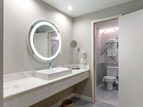 a bathroom with a sink and a mirror and a toilet at Novotel Salvador Rio Vermelho in Salvador