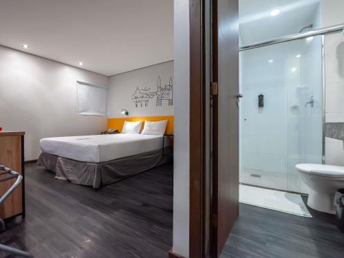 a bedroom with a bed and a bathroom with a shower at ibis Styles Belem Nazare in Belém