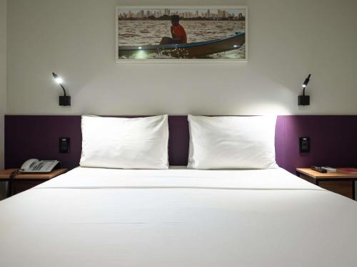 a bed with white pillows in a hotel room at ibis Styles Belem Nazare in Belém