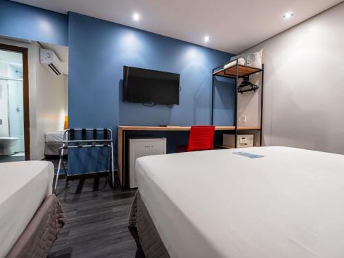 a room with two beds and a desk with a tv at ibis Styles Belem Nazare in Belém