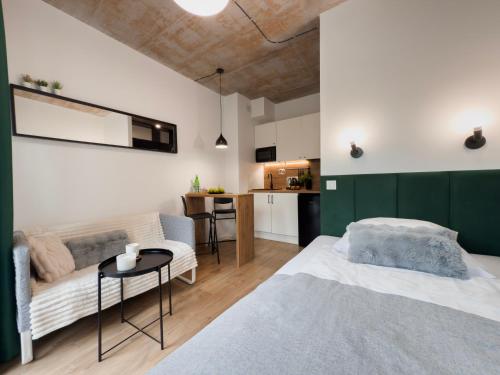 a bedroom with a bed and a couch and a table at Apartamenty Silver Place in Szczecin