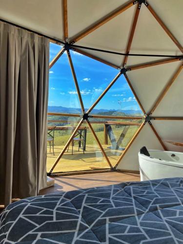 a room with a large window with a bed and a view at Domo com vista do Lago e Montanhas in Igaratá