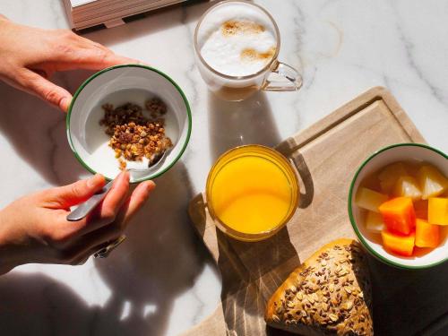 a person holding a bowl of cereal and a glass of orange juice at ibis Styles Amsterdam Airport in Schiphol