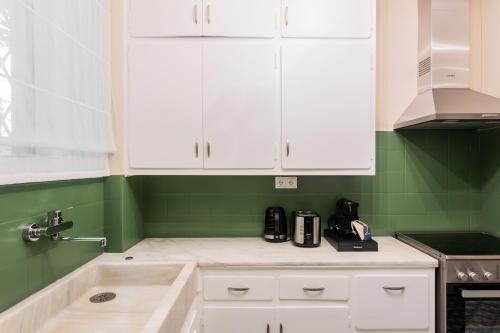 a kitchen with white cabinets and green walls at The Gate by Zoia Living in Athens