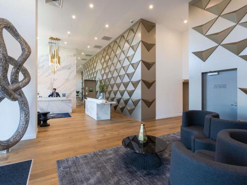 a lobby with a staircase and a reception desk at The Sebel Melbourne Malvern in Melbourne
