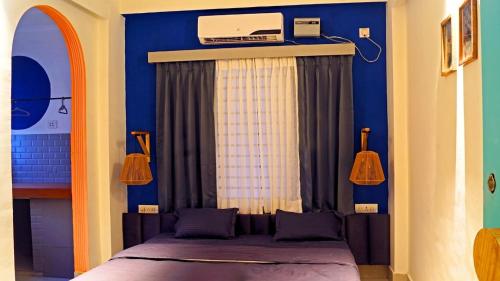 a bedroom with a bed and a blue wall at Hostel De Offlanders Rishikesh - Stay Connect & Explore in Tapovan