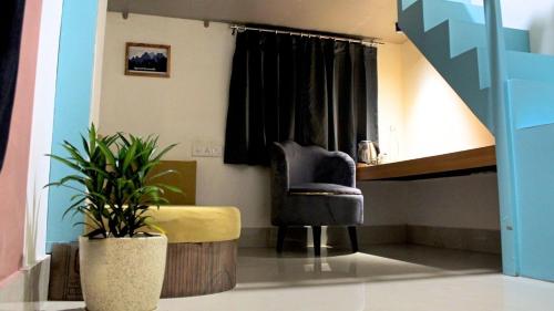 a living room with a chair and a plant at Hostel De Offlanders Rishikesh - Stay Connect & Explore in Tapovan