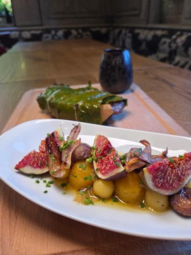 a plate of food with pomegranates and potatoes on a table at Hôtel Restaurant La Couronne by K in Reipertswiller