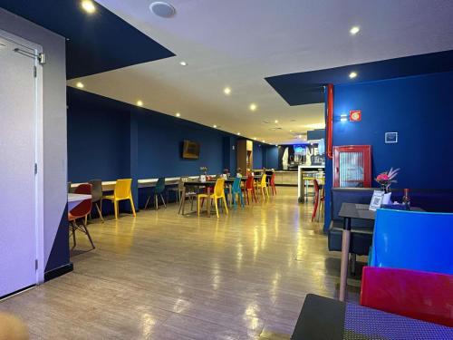 a restaurant with blue walls and tables and yellow chairs at ibis budget Petropolis in Petrópolis