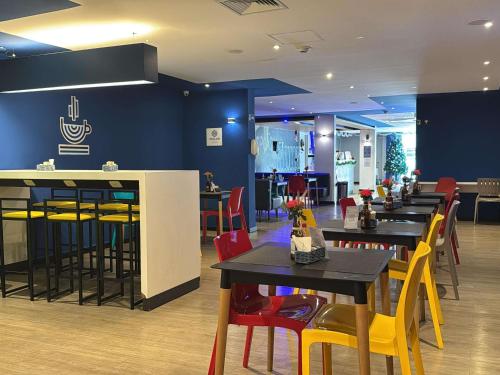 a restaurant with black tables and yellow chairs at ibis budget Petropolis in Petrópolis