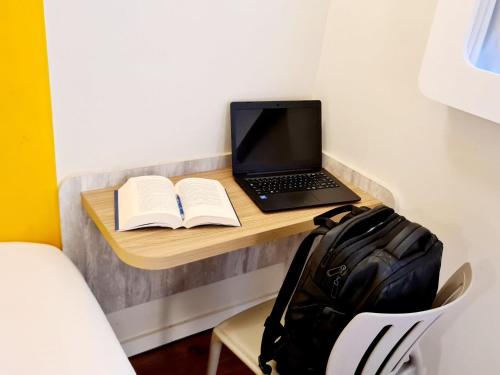 a laptop computer sitting on a desk with a book at ibis budget Petropolis in Petrópolis