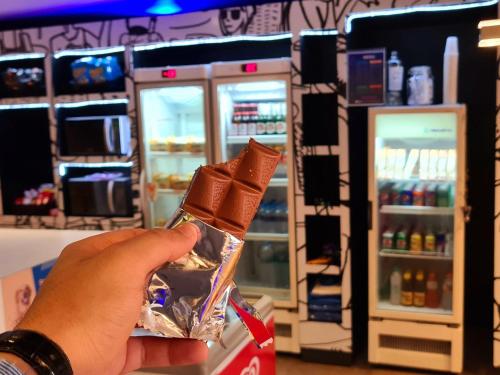 a person holding a piece of chocolate in front of a refrigerator at ibis budget Petropolis in Petrópolis