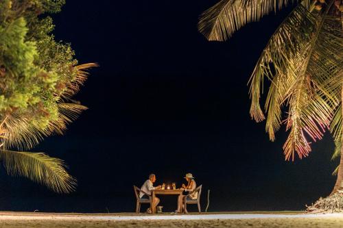 two people sitting at a table at the beach at night at Barramundi in Puttalam
