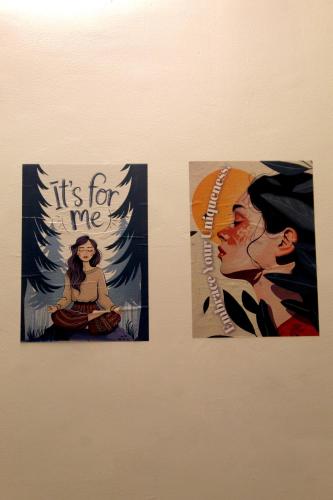 three posters on a wall with a woman at Hostel De Offlanders Rishikesh - Stay Connect & Explore in Tapovan
