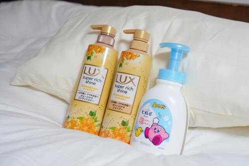 three bottles of cleaner sitting on a bed at Three minutes walk to subway Direct to the airport Umeda business district in Osaka