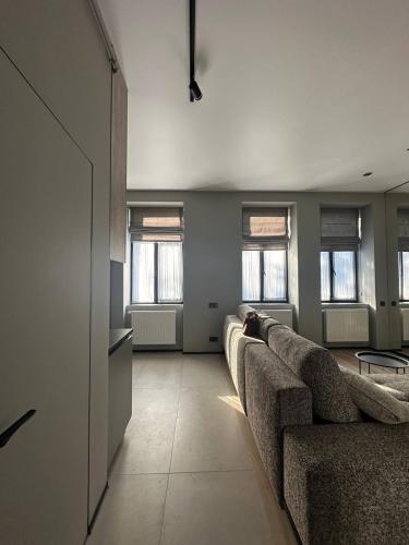 un soggiorno con divano e alcune finestre di Royal jacuzzi apartment on Krehivska 10 st a Lviv