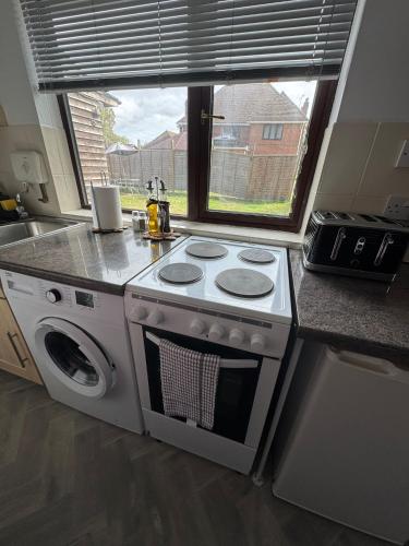 a kitchen with a stove and a sink and a window at Thorpe Park Studio - Detached Stay & Free Gated Parking in Thorpe